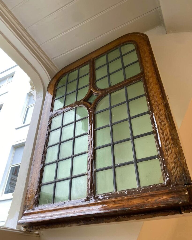 Houten glas-in-loodraam in restauratie met houtrotherstel en schilderwerk in Amsterdam