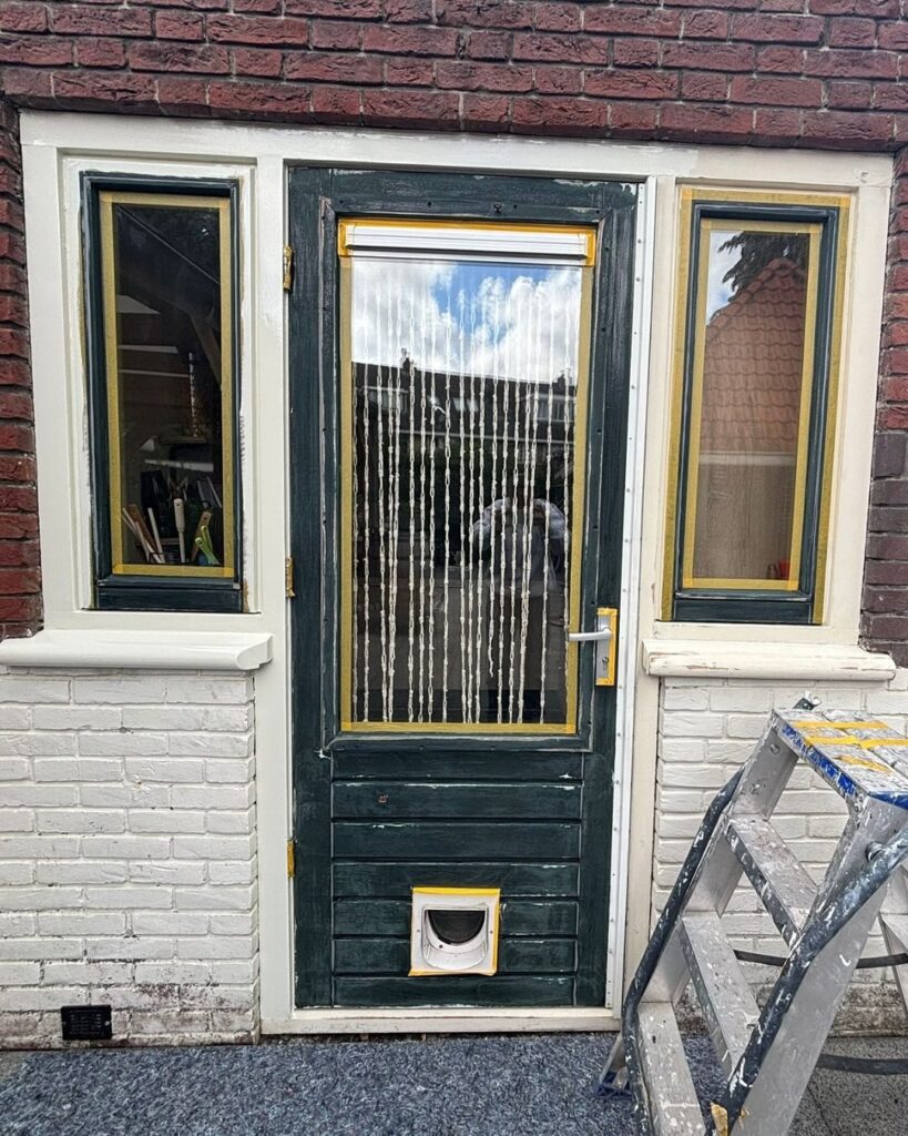 Donkergroene voordeur en kozijnen in de grondverf tijdens buitenschilderwerk in Amsterdam