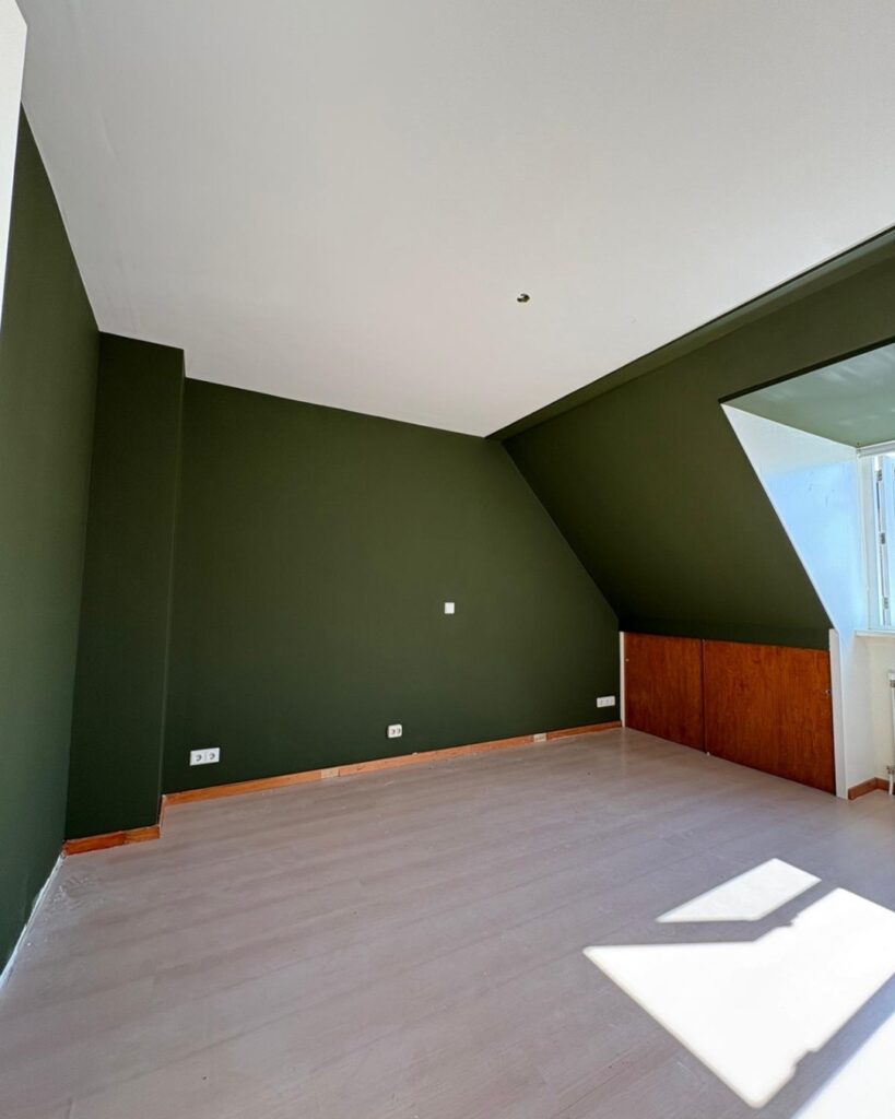 Zolderkamer met groen geschilderde wanden en wit plafond na binnenschilderwerk