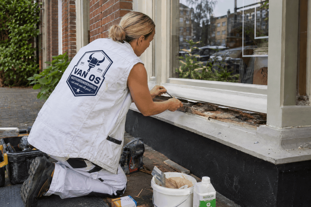 Schilder van Van Os voert houtrotherstel uit aan een aangetaste houten raamdorpel van een woning in Amsterdam