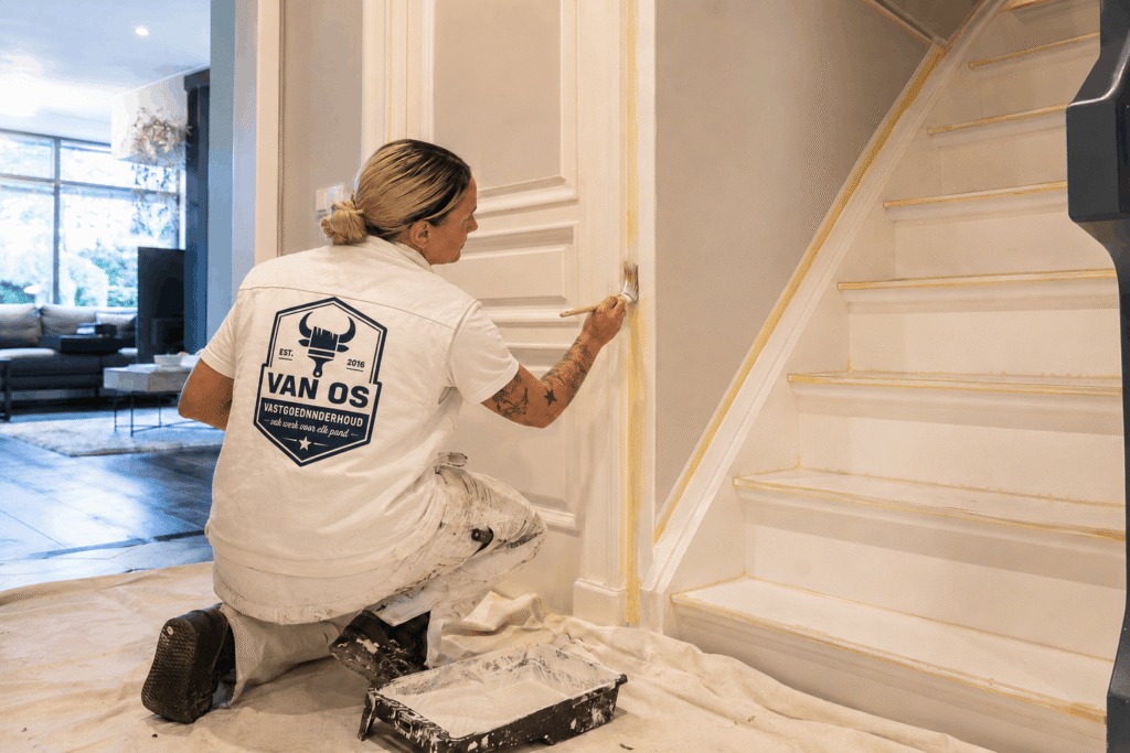 Schilder van Van Os schildert wit trapkozijn tijdens binnenschilderwerk in een woning in Amsterdam