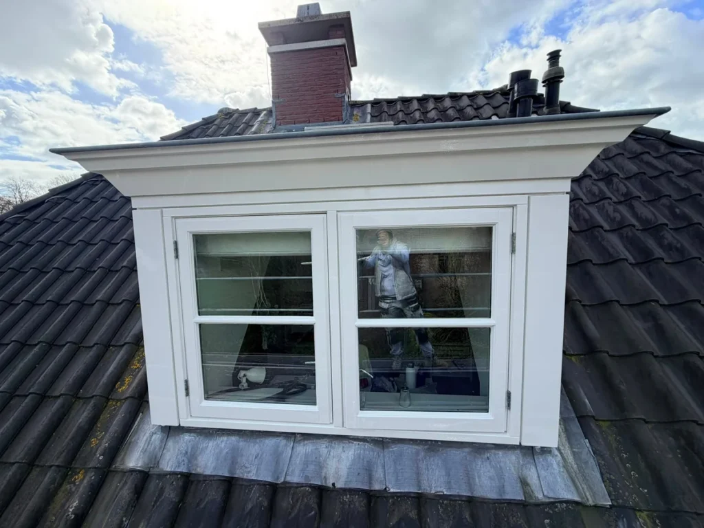 Vers geschilderde witte dakkapel met kozijnen op een pannendak, met bakstenen schoorsteen