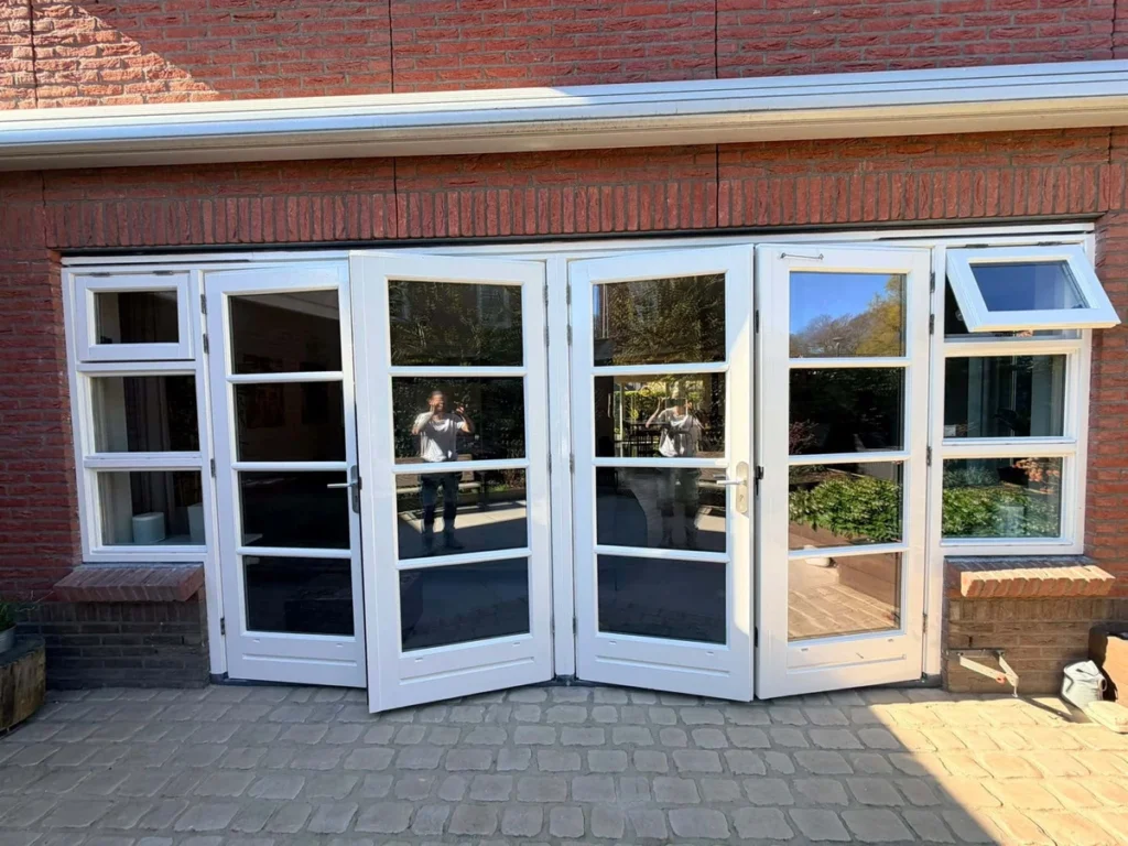 Wit gelakte openslaande tuindeuren in een bakstenen achtergevel na buitenschilderwerk