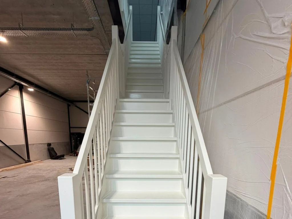 Strak wit gelakte trap met balustrade na binnenschilderwerk in een bedrijfsruimte