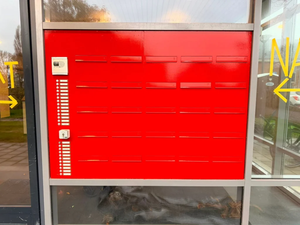Postkastenwand in hoogglans rood gelakt tijdens binnenschilderwerk bij de entree