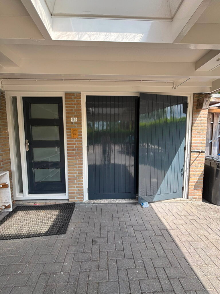 Vers geschilderde antracietgrijze garagedeuren en voordeur van een woning in Lelystad