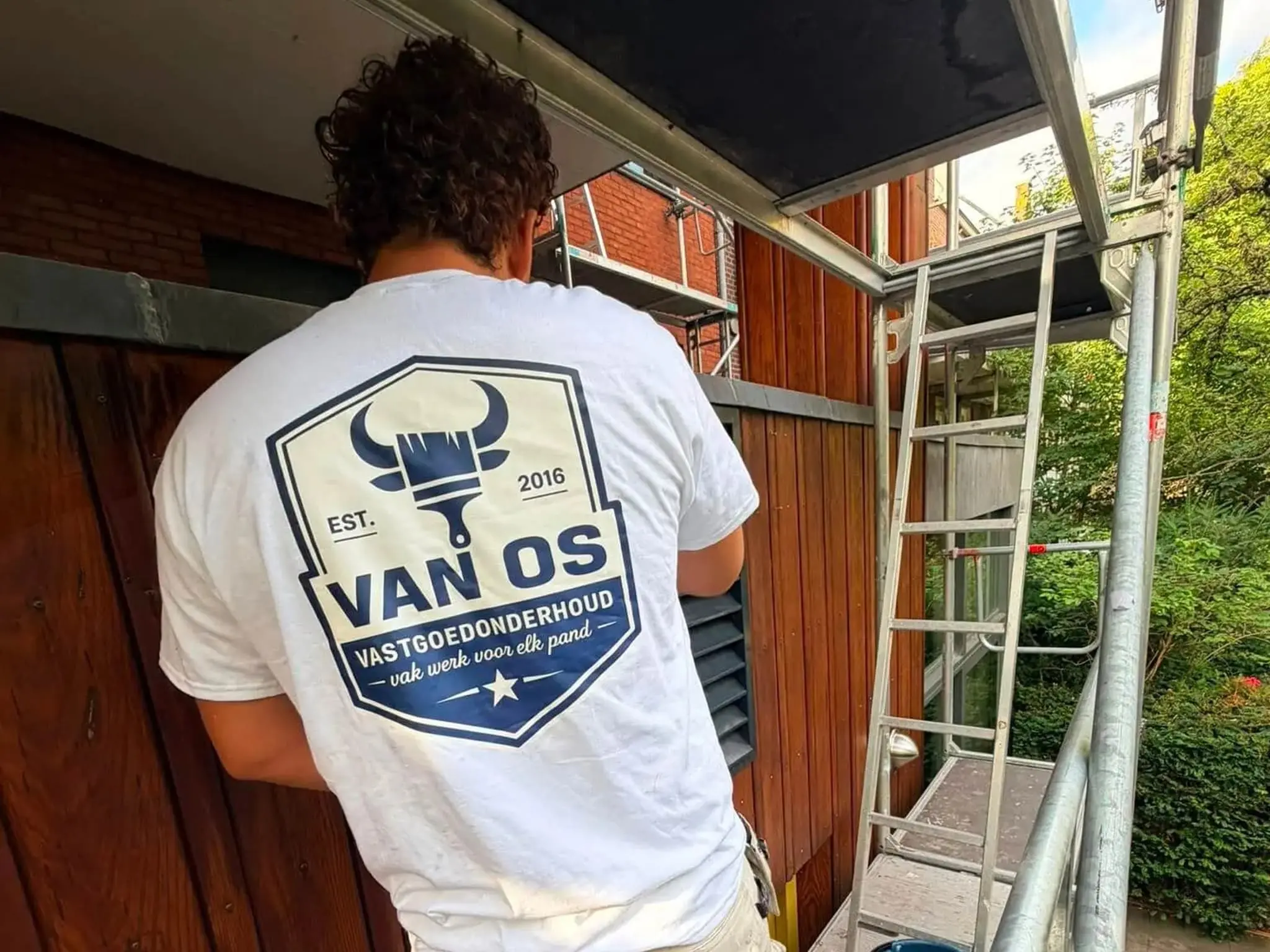 Schilder van Van Os op steiger werkt aan houten gevelbekleding tijdens buitenschilderwerk