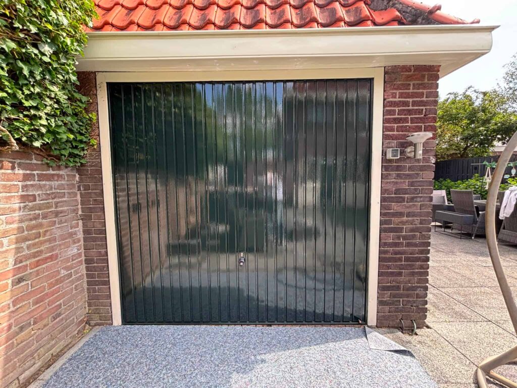 Vers geschilderde glanzend donkergroene garagedeur met crème kozijn na buitenschilderwerk